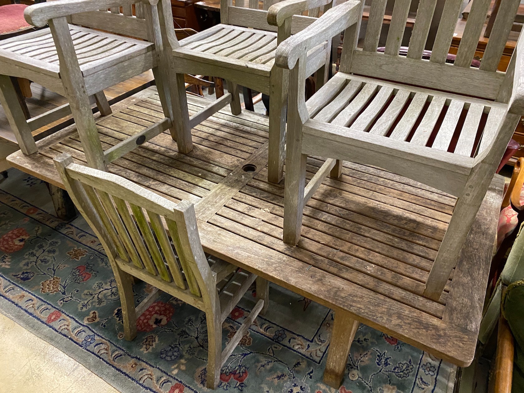 A rectangular weathered teak garden table, length 183cm, depth 92cm, height 73cm and seven Lister teak garden elbow chairs